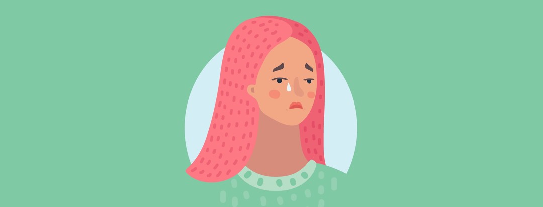 woman with pink hair and green shirt shedding a tear