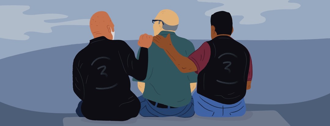 Three older men, sitting on a bench with their arms around each other