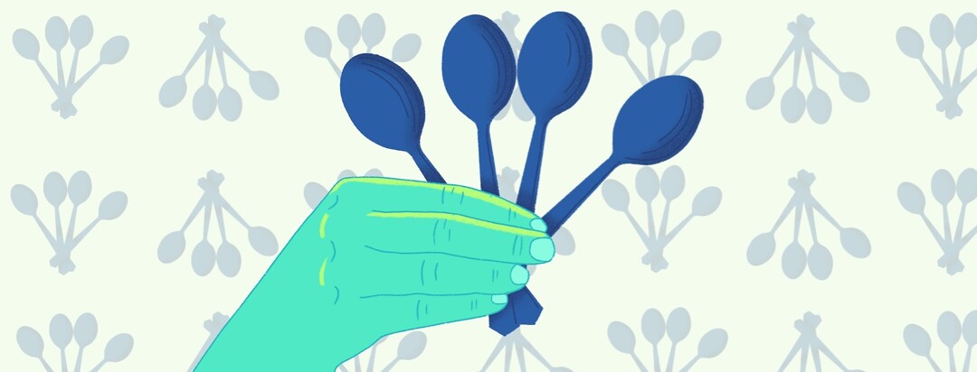 A hand holding four spoons
