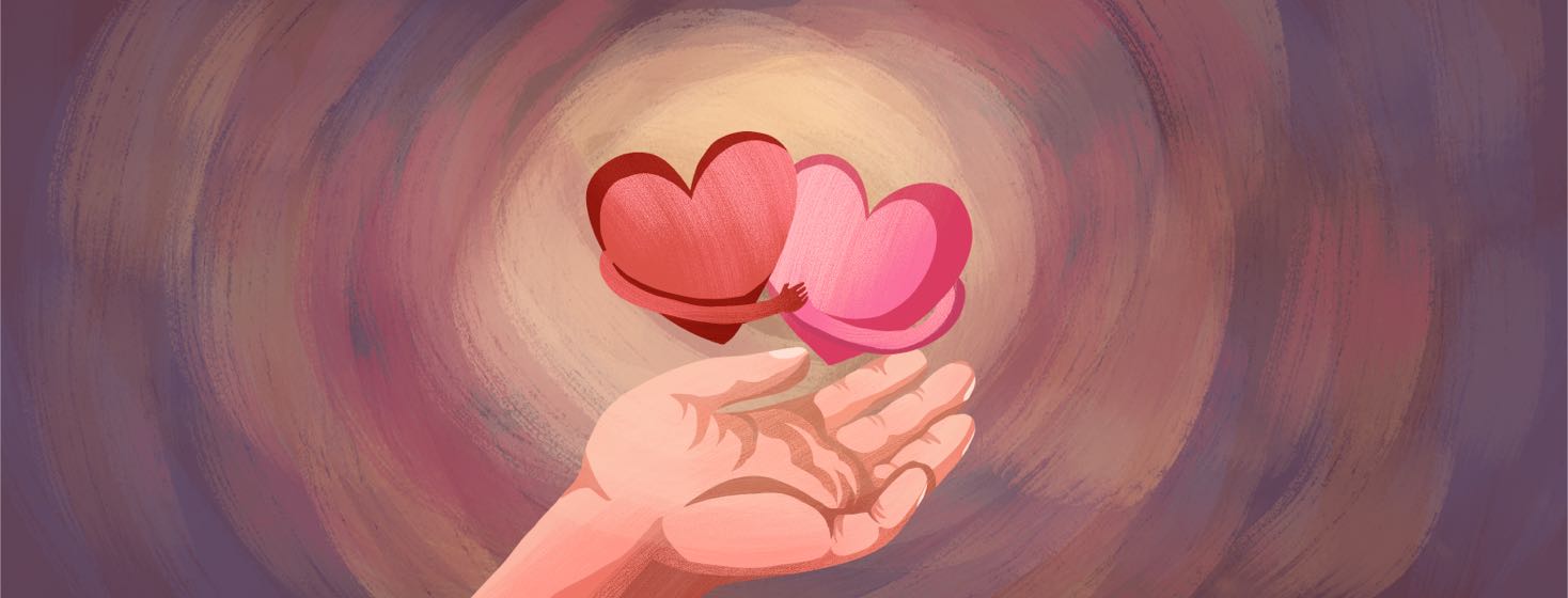 A hand holds up two hearts hugging each other.