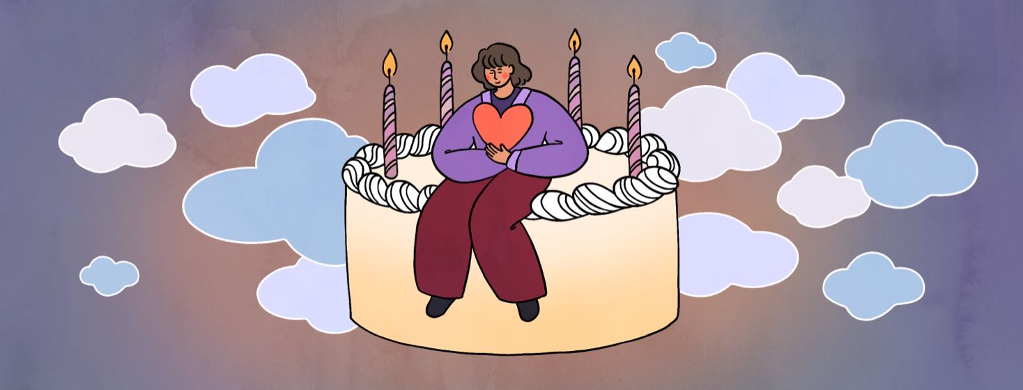 A woman sits on a birthday cake, holding a heart in her arms.
